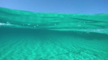 Slow Motion, Half Underwater, Pov: Genç erkek turist güzel Sardunya 'nın güneşli kıyılarına doğru yüzüyor. Turkuaz okyanusta yüzerken nefes kesici İtalyan adasının muhteşem manzarası..