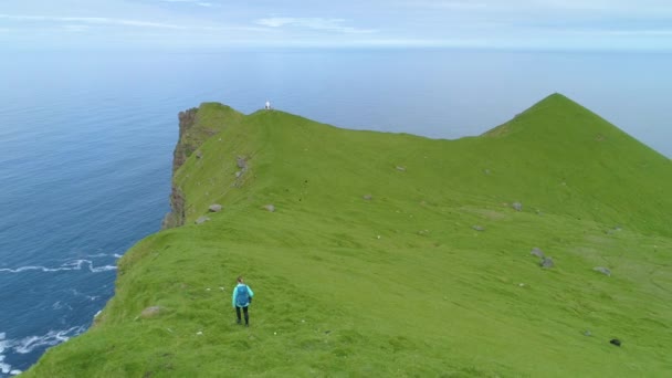 Aerial Flying Woman Hiking Steep Hill Small White Lighthouse Grassy — Stock Video