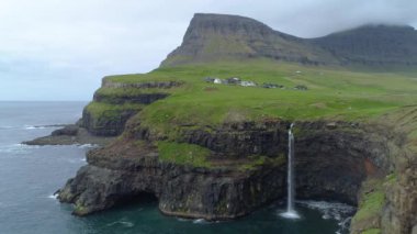 Anteni: Pitoresk köy çimenli dağlar ve bulutlu bir günde muhteşem uçurumlarda nefes kesen Faroe Adaları'altında. Güzel bir İskandinav kırsal muhteşem bir şelale manzarası.