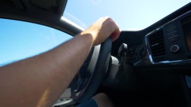 Slow Motion, Close Up, Lens, tanınmayan adam güneşli bir yaz gününde modern bir arabanın direksiyonunu tutuyor. Yetişkin bir erkek, arabasıyla gidip geliyor. Siyah iç tarafı olan elleri kontrol eden araç..