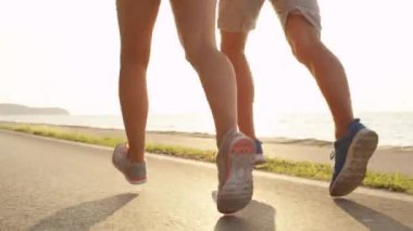 Lens Fişeği, Low Angle: Bilinmeyen genç kadın ve atletik bacaklı bir adam güneşin altında manzaralı sahil yaya yolunda koşuyor. Tanınmayan çift güneşli bir günde deniz kenarında birlikte antrenman yapıyor..