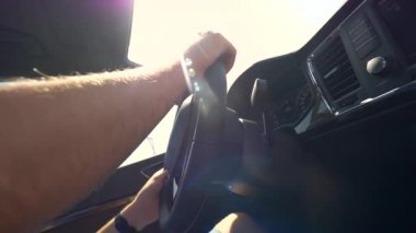 Slow Motion, Close Up, Lens Flare: Tanınmayan bir adamın elleri, siyah, serin bir iç mekanı olan modern bir aracı kullanıyor. Bilinmeyen erkek turistin güneşli bir yaz gününde kiralık araba sürüşünün sinematik görüntüleri..