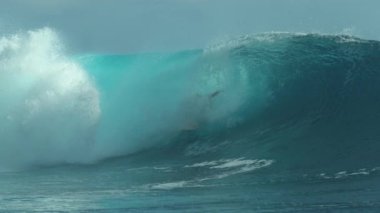 Slow Motion, Close Up: Büyük zümrüt okyanus dalgaları Teahupoo, Tahiti 'deki tatilinin tadını çıkaran neşeli aşırı sörfçünün üzerine sıçrıyor. Tehlikeli bir fıçı dalgasında sörf yapan genç bir erkek sporcunun inanılmaz görüntüsü..