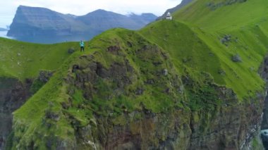 Hava: Genç bir kadın güzel manzarayı gezmeye çıktı ve Kallur Deniz Feneri yükselen çimenli bir uçurumdan okyanusun fotoğraflarını çekti. Manzaralı yeşil dağların nefes kesici görüntüsü.