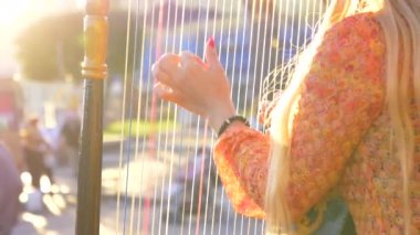 Slow Motion, Lens Flare, Close Up: Güneşli bir günde Roma 'nın güzel sokaklarında arp çalan tanınmayan kadın sokak sanatçısı. Sarı saçlı, meçhul bir kadının sinematik görüntüsü.