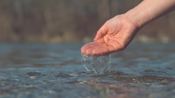 スローモーション マクロ Dof 認識できない少女の穏やかな手は ガラスの川の水をはね 清々しい冷たい湖の水に輝く明るい秋の日差し未知の若い女性によってすくい取られている — ストック動画