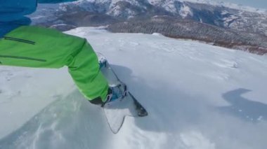 Slow Motion, Low Angle, Selfie: Tanınmayan aşırı freerider kar tozunu snowboard 'uyla püskürtüyor. Serin bir sörf tahtası olan genç bir snowboardcu dağdaki güneşli kış günlerinin tadını çıkarıyor..