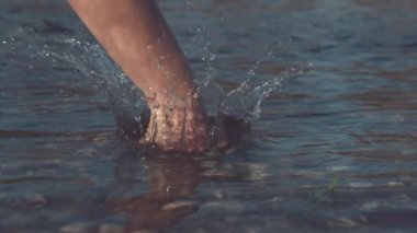 Slow Motion, Close Up, Dof: Vahşi doğada camsı bir gölün yüzeyini yumruklayan tanınamaz şiddet yanlısı kişi. Kızgın insan, nehri vurarak ve temiz suyu sıçratarak stresi azaltır..