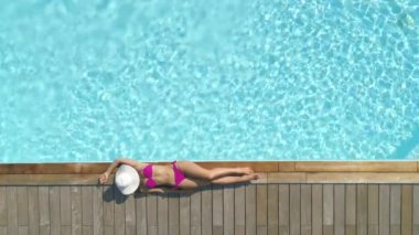 Havadan, Yukarıdan Aşağıya, Sinemagraf: Tanınmayan çekici genç kadın güzel lüks havuz da güneşler. Seksi mayo modeli o serin arka bahçesinde rahatlar ise yüzüne beyaz bir şapka koyar.