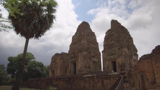 カンボジアの古代仏教寺院の崩壊の石垣に沿って歩いて 遠い森に隠れて 古代から大きな寺院複合体の壮大なショット 美しい忘れられた古い建物 — ストック動画