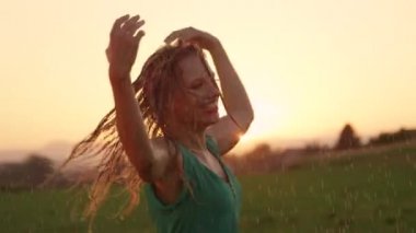 Slow Motion, Portrait, Lens Flare: Gülümseyen kız güzel bir akşam dans ederken sırılsıklam olur. Beyaz dansçı yağmurda takla atarak ve ıslak saçlarını omzuna atarak eğleniyor.