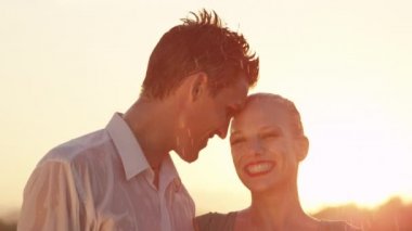 Yavaş Hareket, Portre, Lens Flare: Yakışıklı adam güneşli bir akşam alnından mutlu sarışın kadın öper. Rahat Kafkas çift serinletici bahar yağmurunda eğlenmek gibi sırılsıklam olur.