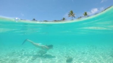 Slow Motion, Half Underwater: Pitoresk kıyı şeridi ve ahşap bir sahil oteli boyunca mükemmel tropikal suda şnorkelli yüzme de tatil genç kadın. Bikinili kız yaz tatilinin tadını çıkarıyor.