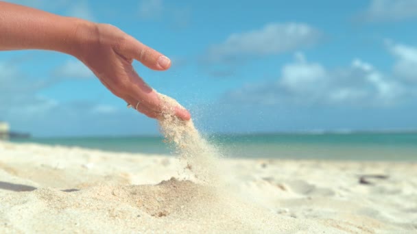 スローモーション クローズアップ コピースペース 彼女は海の近くの静かな砂浜で遊んでいる間 熱い砂の小さな粒がゆっくりと認識できない女性の手から抜け出します 若い女性は熱い砂で遊ぶ — ストック動画