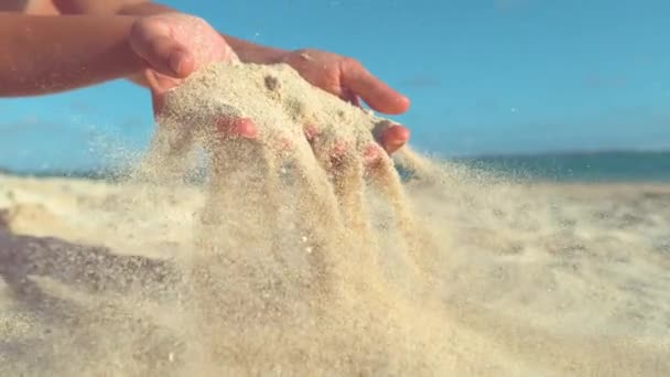 慢动作 温和的夏日微风从俏皮女孩柔软的手中扫走沙 在美丽的库克群岛 在偏僻的阳光海滩飞过小颗粒的沙粒电影拍摄 — 图库视频影像