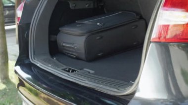 Yakın: Bagaj, onun büyük siyah araba geniş önyükleme ambalaj tanınmaz halde genç gezgin güneşli banliyö evin önüne park etmiş. Seyahat çantaları onun Suv koyarak Beyaz tişörtlü bilinmeyen adam.