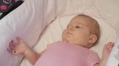 Slow Motion, Close Up: Oyuncu küçük kız bebek arabasının konforundan güneşli doğasına bakıyor. Pembe tulumlu sevimli bebek parkta ailesiyle yürürken bir arabada dinleniyor..