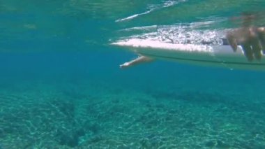Slow Motion, Close Up, Underwater: Muhteşem Fiji sürme genç sörfçü onun tahta üzerinde yatıyor ve sıraya doğru kürekler. Pro sörfçü epik Cloudbreak dalgalar binmek için kıyıdan uzak kürek