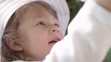 Slow Motion, Close Up, Portrait, Dof: Oyuncaklarını ailesine gösteren beyaz bir şapka takan güzel bir bebek. Onu kabarık yeni oyuncak ile anne ve babası lovely küçük bebek kızı dalgalar.