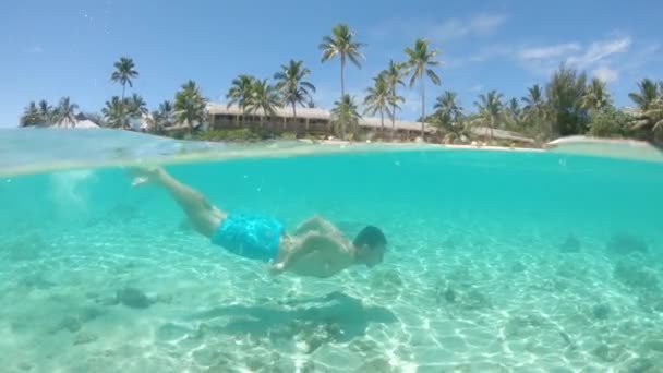 スローモーション ハーフ水中 絵のように美しい熱帯の島の白い砂浜に沿って泳ぐ若い男 陽気な男性は 静かなガラスの海でダイビングによって冷却します 素晴らしい夏休みの活動 — ストック動画