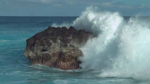 慢动作 强大的海浪在崎岖的异国海中溅过一块大岩石 在岩石热带海岸附近的黑色岩石上剧烈的破浪发泡的壮丽景色 — 图库视频影像