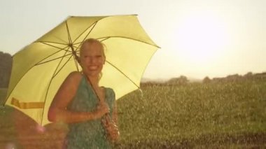 Slow Motion, Close Up, Lens Flare: Altın ışıklandırılmış yağmurlu kırsalda eğlenceli Kafkas kadın dans ediyor. Sarışın at kuyruğu neşeli spin ve serinletici bahar gününde doğada dansları ile güzel kız.