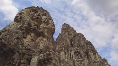Düşük Açı: Kamboçya'daki antik Budist tapınaklarının yükselen kalıntılarının nefes kesici görünümü. Solan duvarlarda farklı yüzleri ile Güzel eski Asya kulesi turistler için inanılmaz bir manzara sağlamak