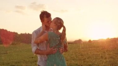 Slow Motion, Close Up, Lens Flare: Kucaklanan genç aşıklar gün batımında yağmurlu yeşil kırsal tutkuyla öpücük. Kaygısız erkek arkadaşı ve kız arkadaşı öpücük ve nefes kesen sabah birbirlerine tutun.