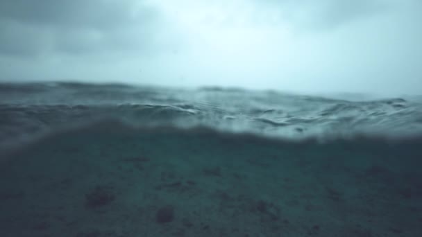 スローモーション ハーフ水中 マクロ Dof カメラを越えて 空の海底の上に転がる穏やかな深い青い海の波の美しいショット 激しい熱帯暴風雨の前に撮影された静かな海 — ストック動画
