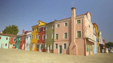 Burano İtalya, Haziran 2017: Muhteşem Venedik güneşli bir günde renkli evlerin pitoresk bir satır boyunca yürüyüş. İtalya'da güzel binaların canlı boyalı cephelerin çarpıcı görünümü.