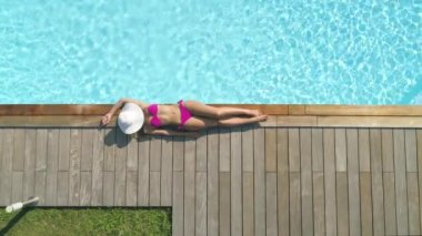 Havadan, Yukarıdan Aşağıya, Sinemagraf: Bilinmeyen güzel genç kadın güzel bir yaz gününde arka bahçesindeki havuzunun yanında güneşliyor. Güzel özel havuz tarafından tek başına rahatlatıcı seksi mayo modeli üzerinde Uçan.