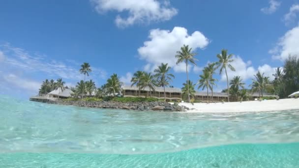 ハーフ水中 美しい熱帯の自然は 砂浜と静かなガラスの海の壮大な景色を望む離島の木造ホテルを囲みます — ストック動画