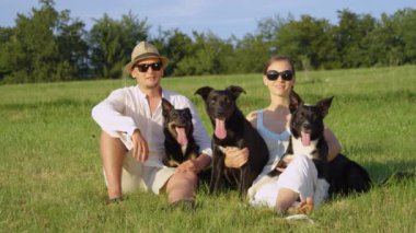 Yavaş Hareket, Portre: Mutlu genç adam ve kadın tutan ve onların frisky siyah sınır collie köpekler petting. Neşeli Kafkas çift itaatkar yavruları ile çimenli alanda oturan pozlar.