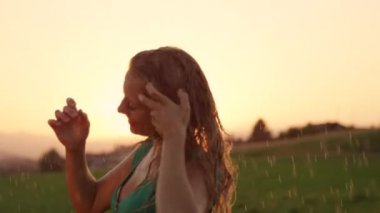 Slow Motion, Portre, Lens Flare: Mutlu genç kadın kırsal taze bir yağmurlu sabah onu ıslak sarı saçları ile oynar. Altın ışıklı doğada tek başına dans neşeli kız Sinematik atış.