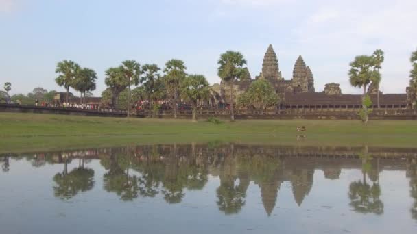 无数人走向柬埔寨令人叹为观止的佛教寺庙 美丽的热带棕榈树和平静的湖泊环绕着吴哥窟拥挤的入口 热门旅游景点 — 图库视频影像