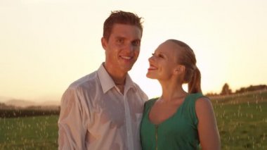 Yavaş Hareket, Portre, Lens Flare: Oyuncu kadın yakışıklı genç adam yağmurda yanak bir öpücük verir. Kafkas çocuk pitoresk kırsal bir bahar duş sırasında kız arkadaşı tarafından öpüldü alır