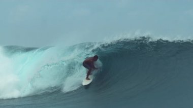 Yavaş Hareket, Close Up: Korkusuz genç profesyonel surfboarder Tahiti bir camsı zümrüt okyanus dalga sürmek. Güneşli plajlara doğru çökmesini büyük bir varil dalga sörf ekstrem sporcu muhteşem atış.