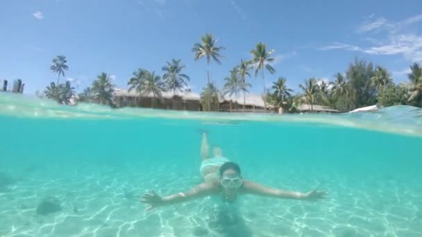 慢动作 半水下 活跃年轻女子暑假浮潜通过相机 女孩在绿松石比基尼浮潜周围风景如画的玻璃海洋靠近田园诗般的热带海滩 — 图库视频影像