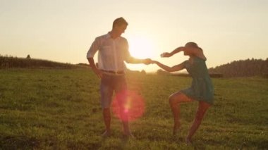 Slow Motion, Lens Flare: Mutlu genç çift güzel bir turuncu ışıklı akşam sakin yağmurlu kırsal yalınayak dansları. Onlar yeşil doğada incelikle dans ederken Kaygısız erkek ve kadın öpücük.