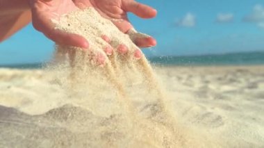 Yavaş Hareket, Yakın Çekim: Bilinmeyen genç kadın sıcak kum onun nazik parmakları ile düşmek ve güneşli sahile geri sağlar. Kadın turistin kavrayışından uçan kaba kum parçacıklarının soğuk yavaş hareketi.