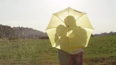 Slow Motion, Close Up, Lens Flare: Mutlu genç çift yağmurda öper ve pitoresk akşam kırsal boyunca romantik bir yürüyüş devam ediyor. Gülümseyen kadın ve adam yağmurlu yaz günü zevk.