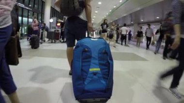 Tayland Havaalanı 2018, Diğer turistler ve yerliler dolu yoğun havaalanı etrafında bagajını taşıyan flip flop genç erkek backpacker Close Up.