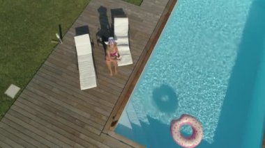 Slow Motion, Aerial, Pov: Kızgın genç kadın, arka bahçesindeki havuzunda güneşlenirken fotoğraflarını çekerek uğuldayan drone'u kovalar. Rahatsız sarışın kız onun gizlilik işgal uzaktan kumandalı uçak çökmeye çalışır.