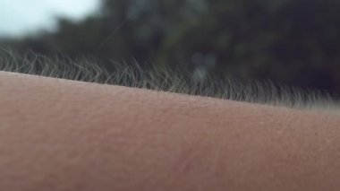 Close Up, Macro, Dof: Okyanustan gelen güçlü rüzgarlar bilinmeyen kişinin yükseltilmiş kol kıllarını çılgınca çırpındırıyor. Kadın tüyleri diken diken olur ve tropik bir yağmur fırtınasına yakalandıktan sonra titremeye başlar..