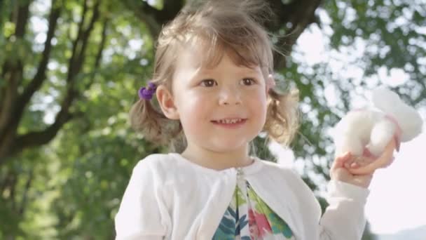 慢动作 迷人的小女孩玩和跳与她的蓬松的玩具兔子 美丽的幼儿女孩与可爱的辫子享受一个可爱的一天在公园玩她最喜欢的玩具 — 图库视频影像