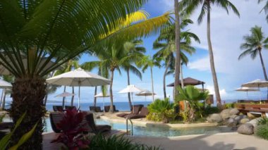 Çarpıcı cam gibi havuzun ortasında lüks beachfront akar küçük yapay şelale otel personeli tarafından temizlenmektedir çare. Paradise Island resort üzerinde boş lüks havuzu ve lounge koltukları