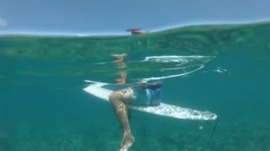 Slow Motion, Underwater, Half-Half: Fit erkek turist onun sörf tahtası üzerinde oturur ve Cloudbreak dalgalar Pasifik popüler sörf yerinde rulo beklerken egzotik deniz manzarası etrafında bakar.
