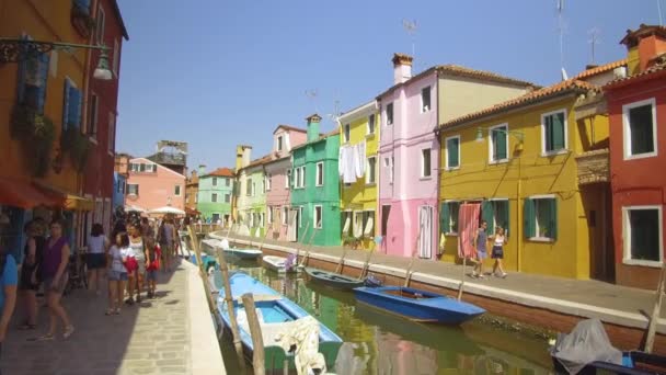 ブラーノイタリア 2017年6月 息をのむようなヴェネツィアでカラフルな家と穏やかなチャネルを通り過ぎて走る混雑した通りを歩く 晴れた夏の日に絵のように美しいイタリアの町を見回す旅行者 — ストック動画