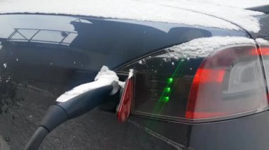 Yakın: Parlak yeşil ışık titreşim ve serin elektrikli otomobil tamamen şarj sinyal. Soket bir soğuk kış gününde .şövalye koşarak futuristik bir aracın içine koymak bir güç tak görüntüsünü kapatmak.