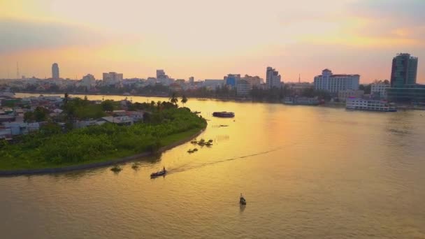 航空写真 穏やかな川の上やベトナムの町の方に飛んで牧歌的な日当たりの良い夜 小さなボートで地元の人々 がアジアの小さな町を流れる美しい熱帯の川に沿ってクルーズします — ストック動画